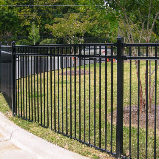 Flat top flat bottom, three rail fencing surrounding public green space next to a parking lot