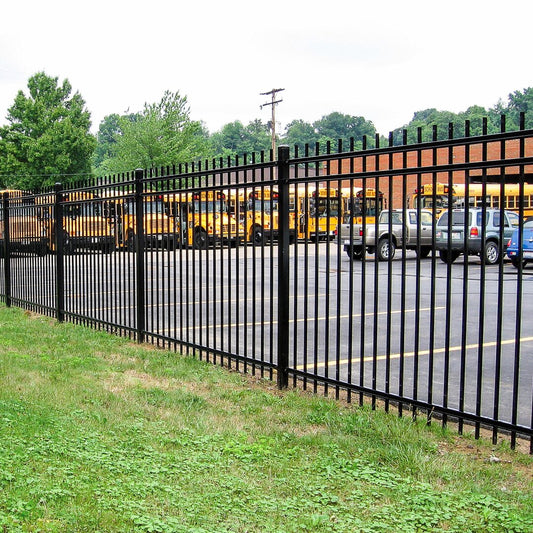 Extruded top extruded bottom, three rail, commercial fencing surrounding a public school parking lot full of buses
