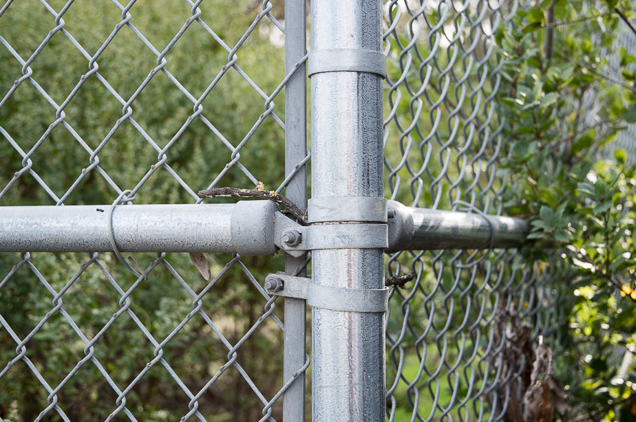 Close-up of a chain-link fence assembly at the corner post showing various fittings