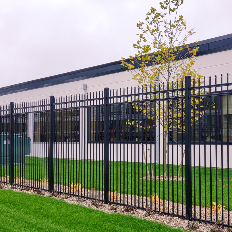 Pressed spear flat bottom, three rail fencing, in front of a windowed building