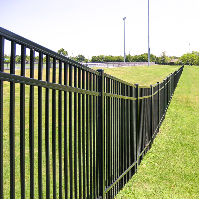 Flat top extruded bottom, three rail fencing near a public field