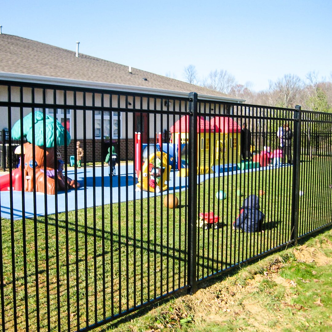 Flat top flat bottom, three rail fencing surrounding a playground with children playing