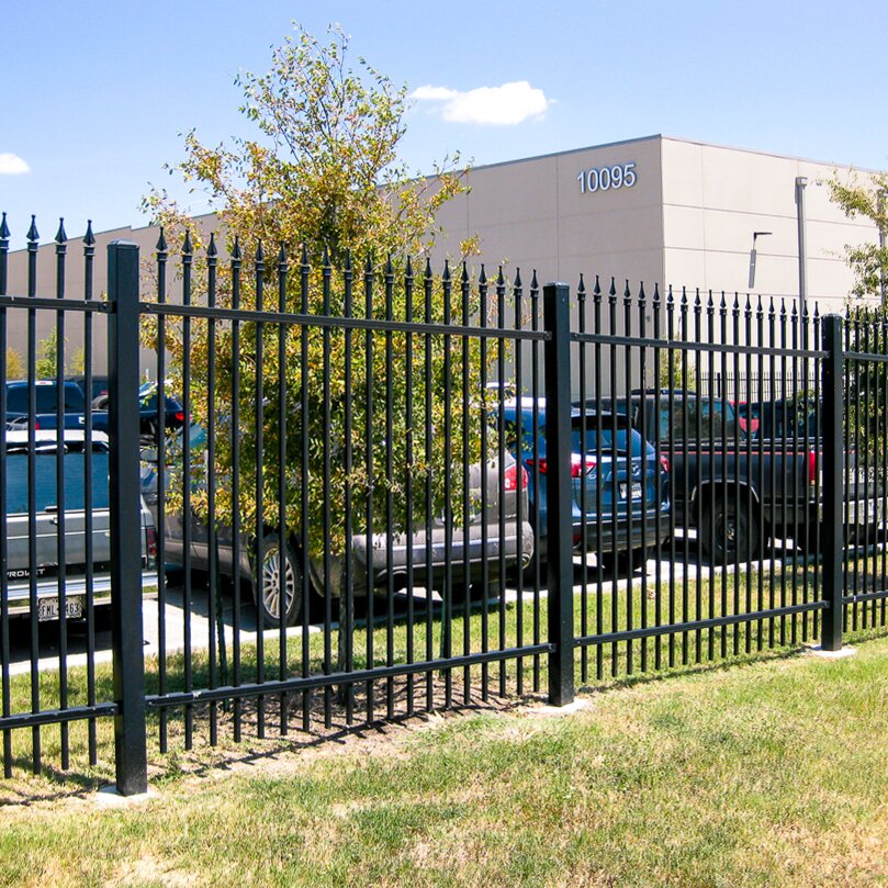 Finial top extruded bottom three rail commercial panel in front of a business parking lot