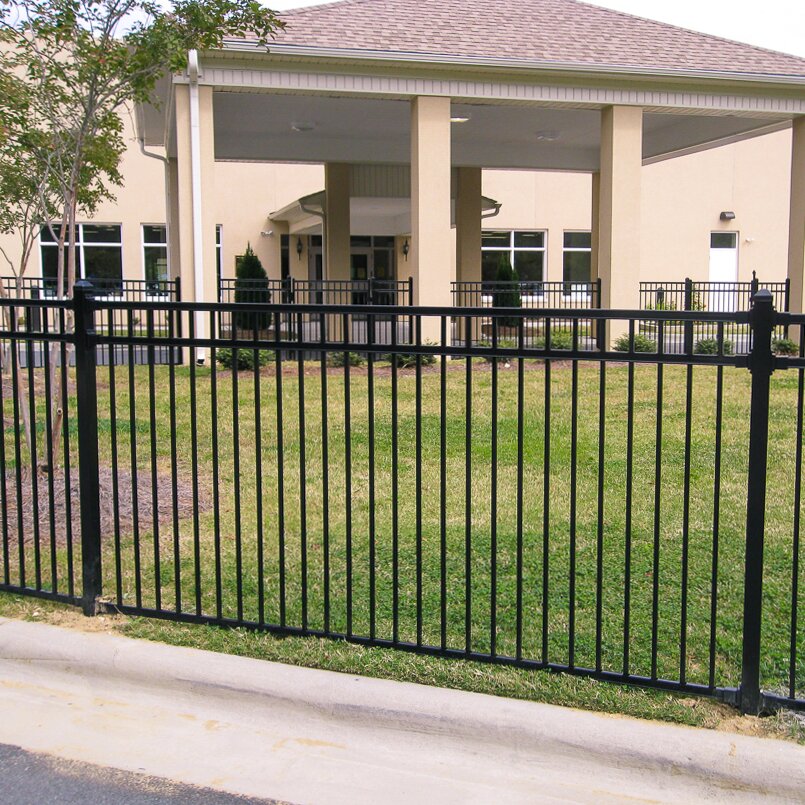 A black metal commercial fence installed in front of a building's entrance, with ornamental design