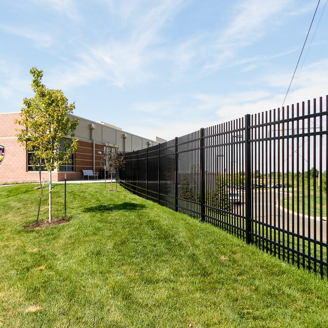 Extruded top extruded bottom, four rail, commercial fencing around a driveway at an office building