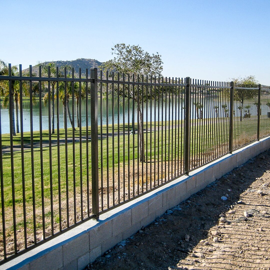 Extruded top flat bottom fencing, mounted on top of a small concrete wall around a lake