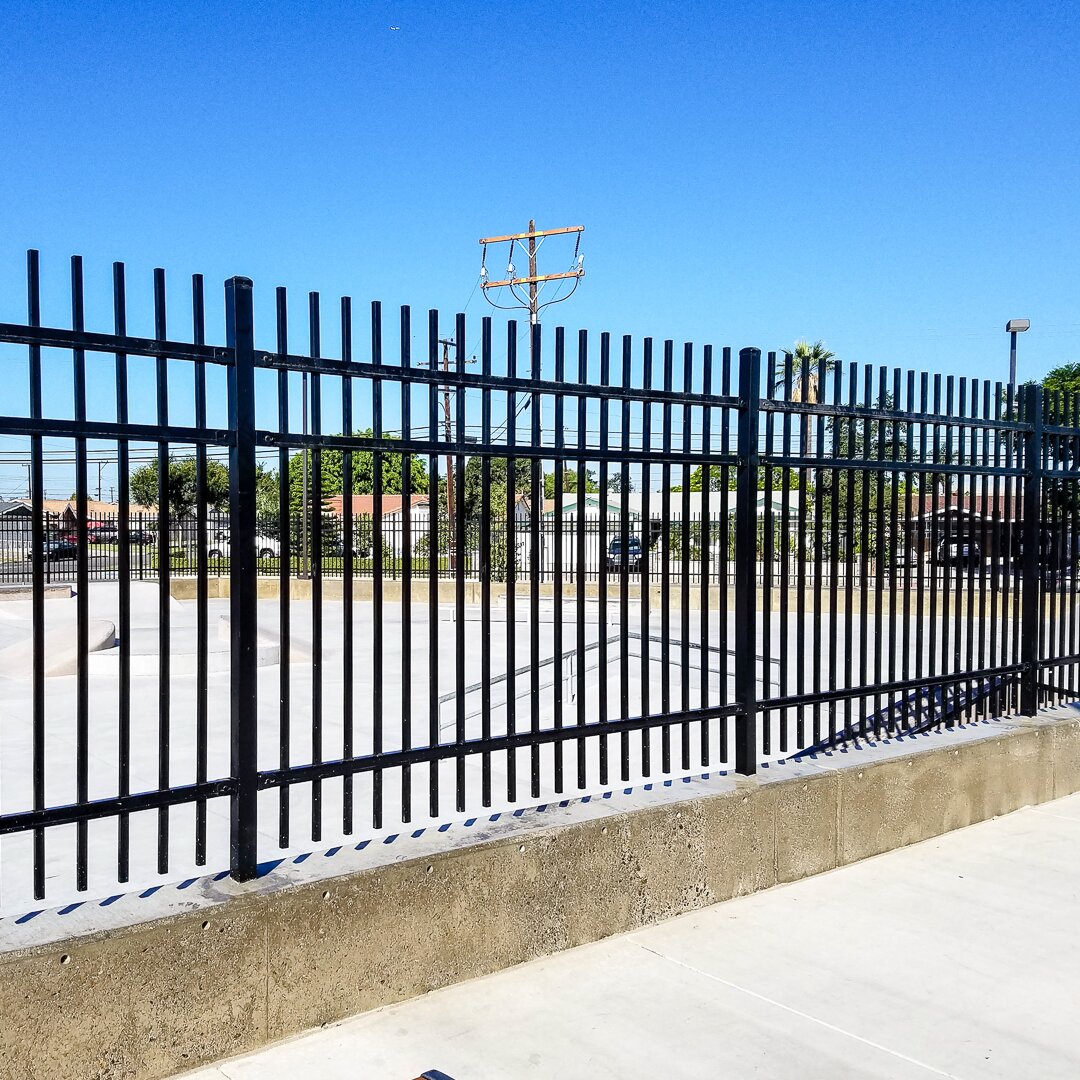 Extruded top extruded bottom fence mounted on a concrete wall around a skate park