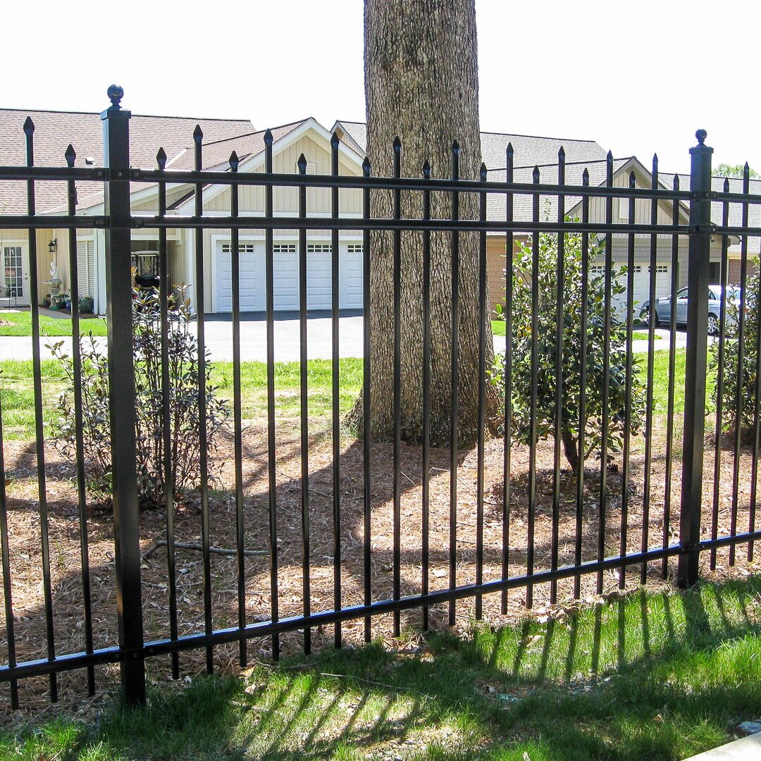 Alternating height pressed spear top extruded bottom, three rail, fencing surrounding homes in a gated community