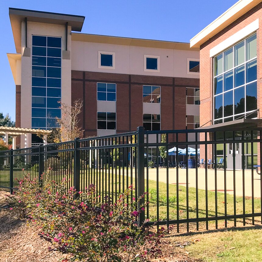 Flat top extruded bottom, three rail fencing, surrounding a eating area outside at a university