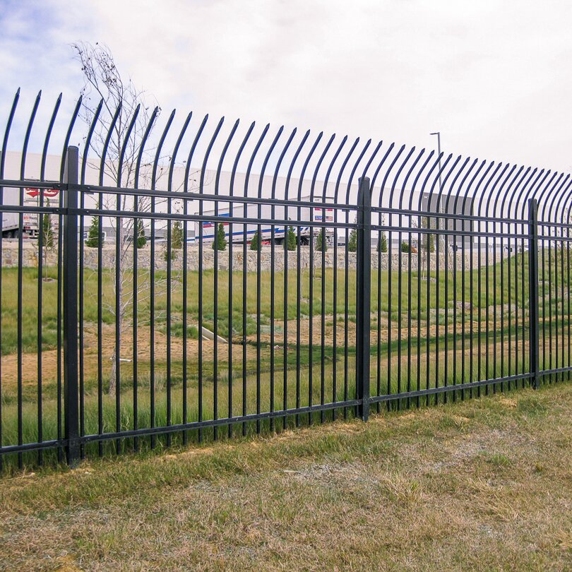 Anti-climb, heavy duty, commercial fencing with press spear tips in front of a warehouse facility